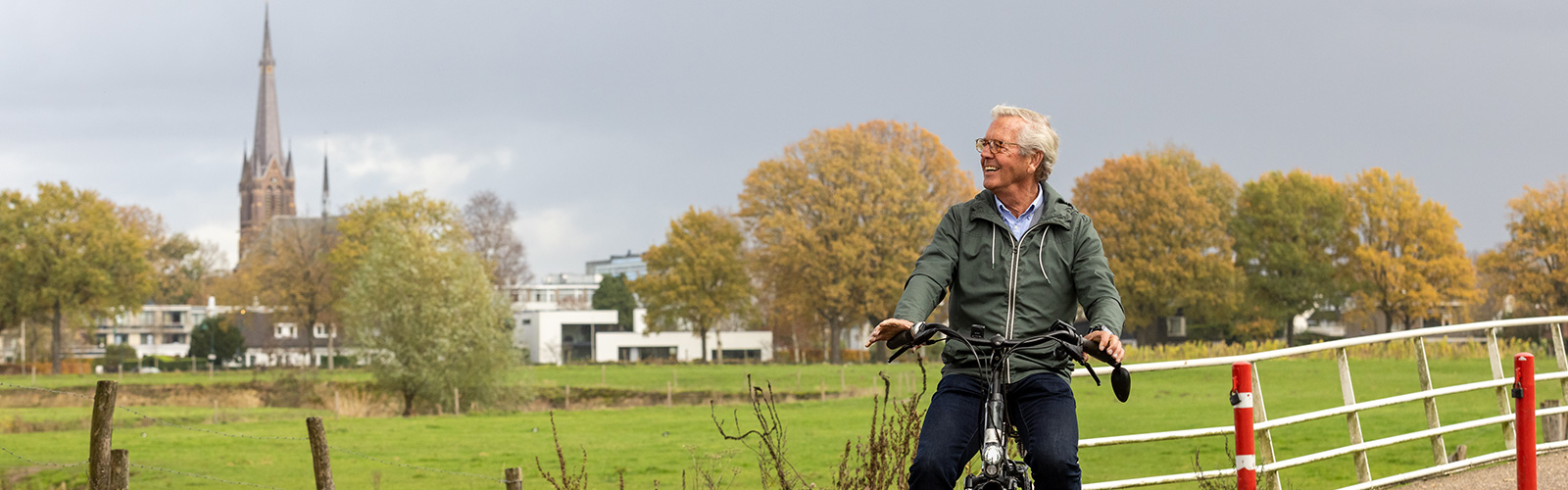 fietser rijdt door de weilanden nabij een dorp.