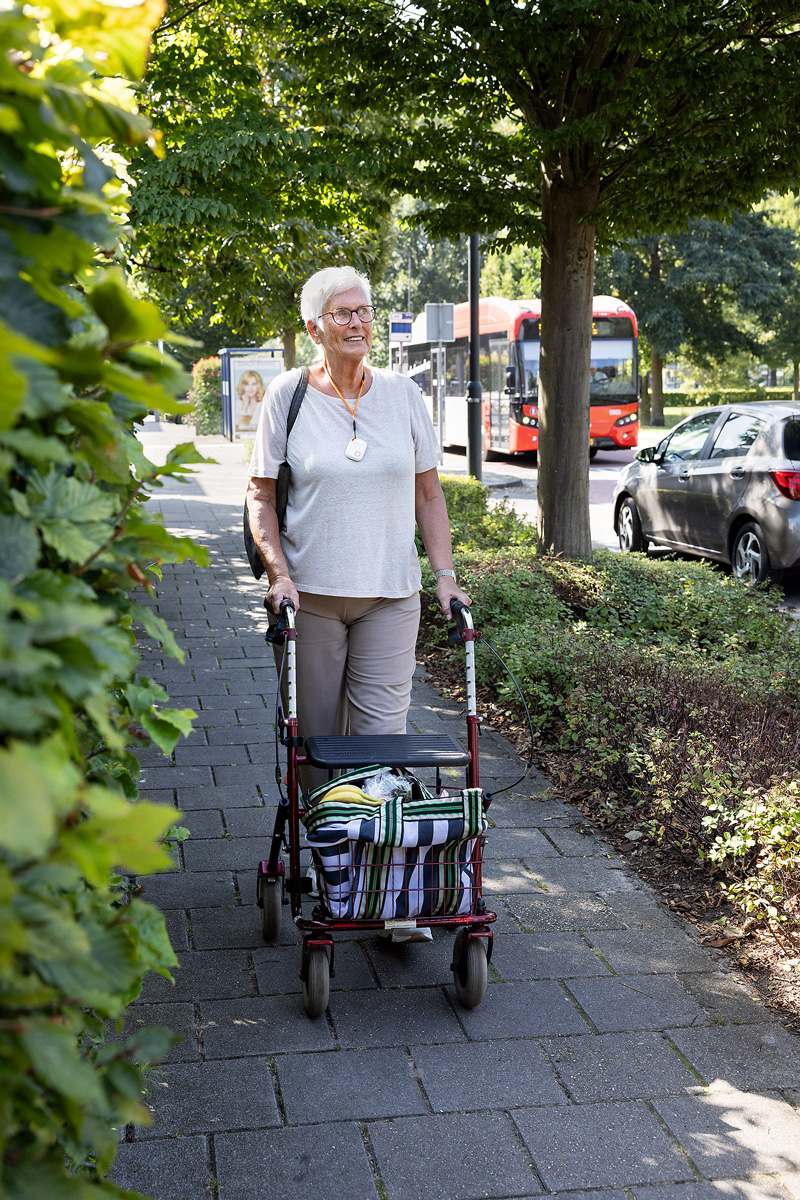 Vrouw met rollator. Om haar hals draagt ze een alarmknop.